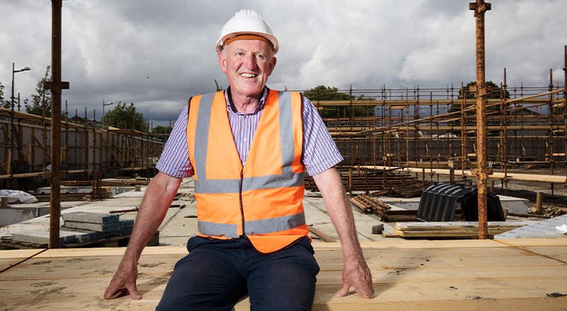 Hugh Brennan in high vest sitting on a building site 